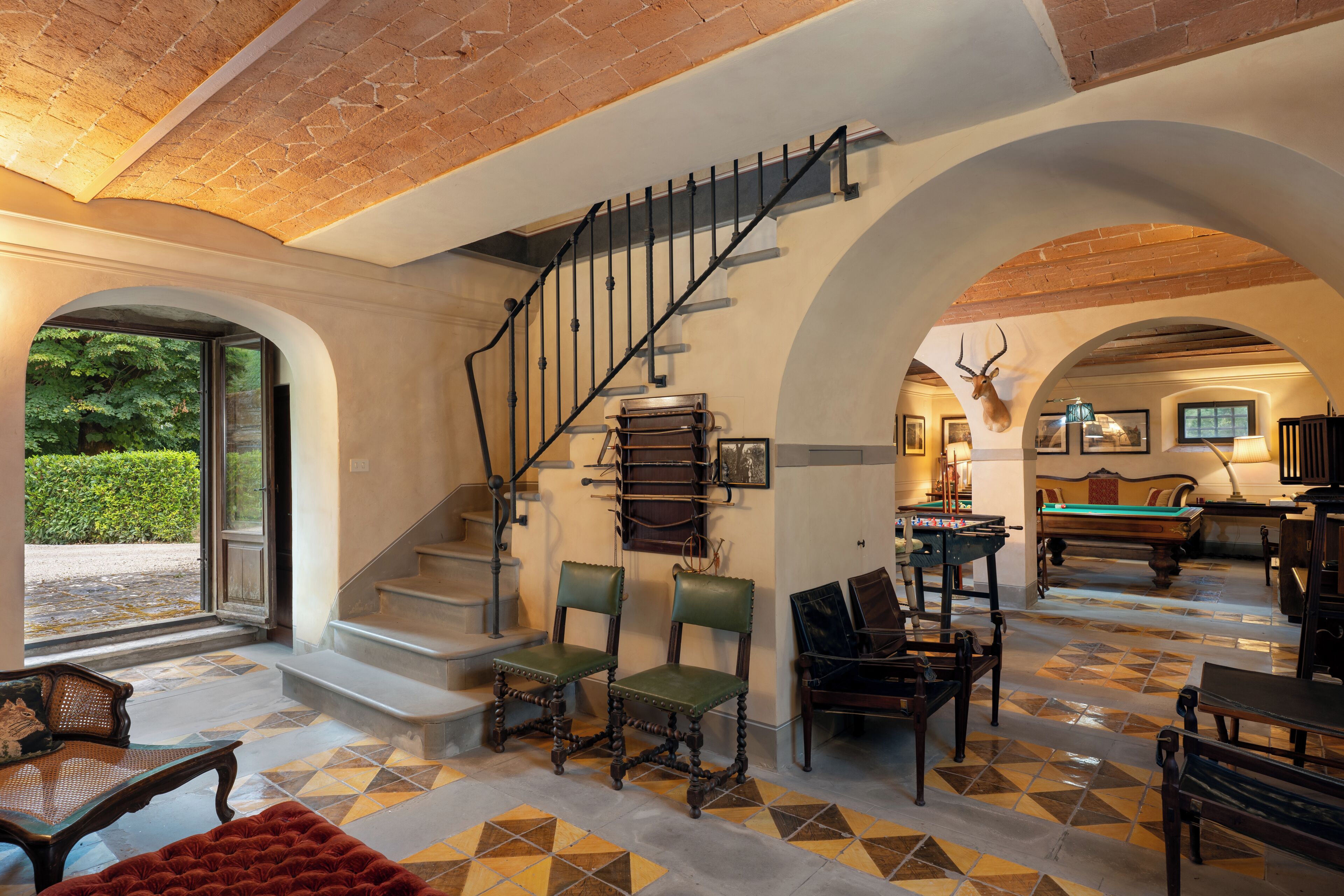 A spacious room with a staircase, a billiards table, and a pool table.