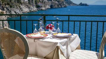 Una mesa para dos con vistas al mar y a un litoral rocoso.