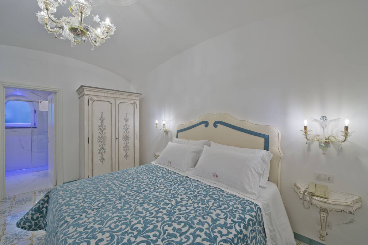 Una camera da letto con un letto, un armadio, un comodino e un telefono fissato alla parete.