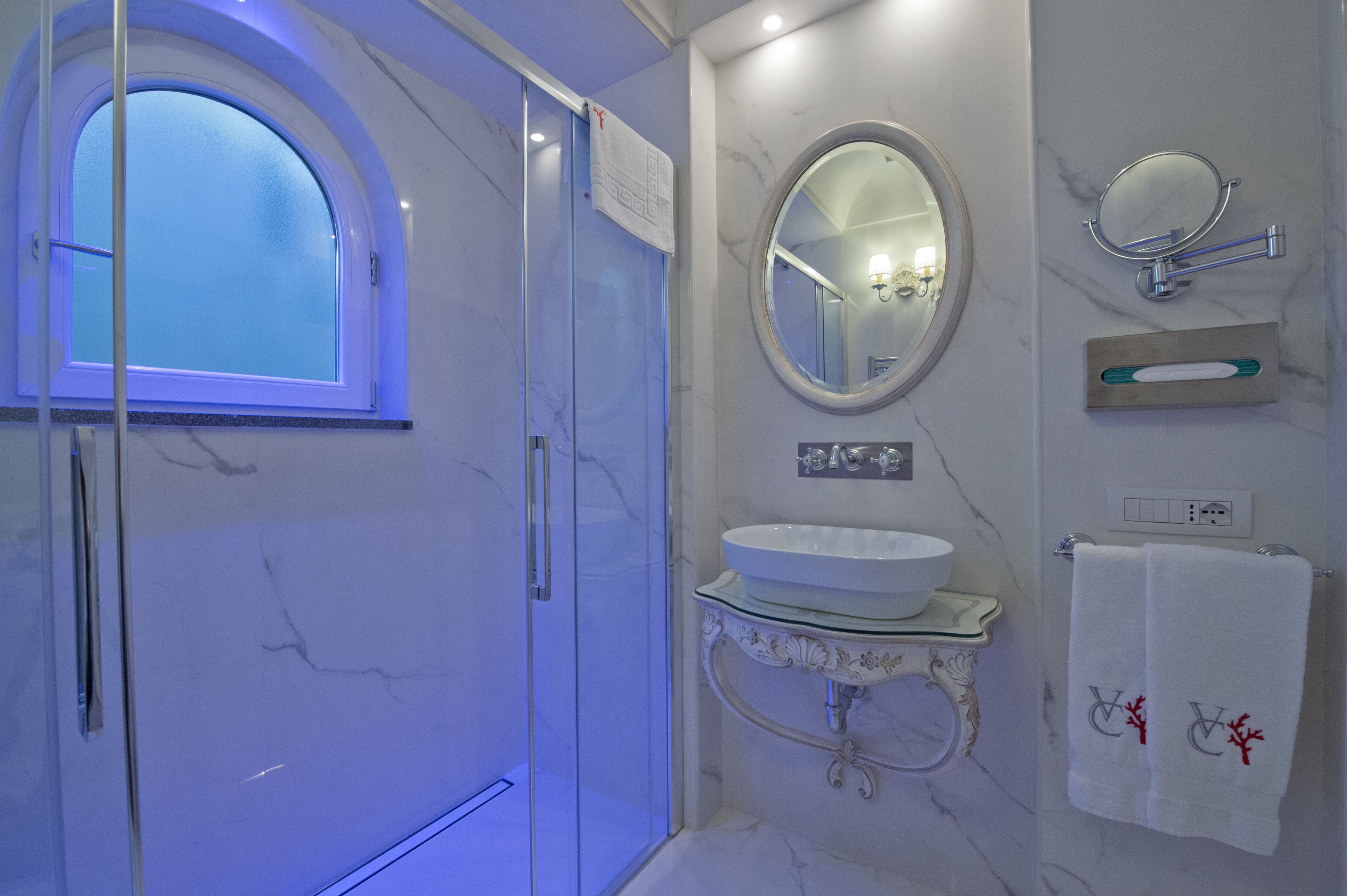 A modern bathroom with a glass-enclosed shower, a marble sink, and a large mirror.