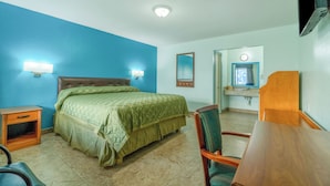 A hotel room with a bed, a desk, a chair, a nightstand, a mirror, and a television. - Budget Inn By OYO Edinburg Hwy 281 (Edinburg)