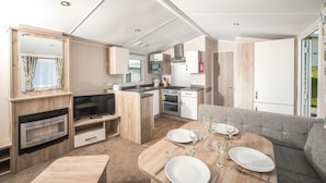 Un intérieur de camping-car moderne comprenant un coin repas, une kitchenette et un téléviseur.
