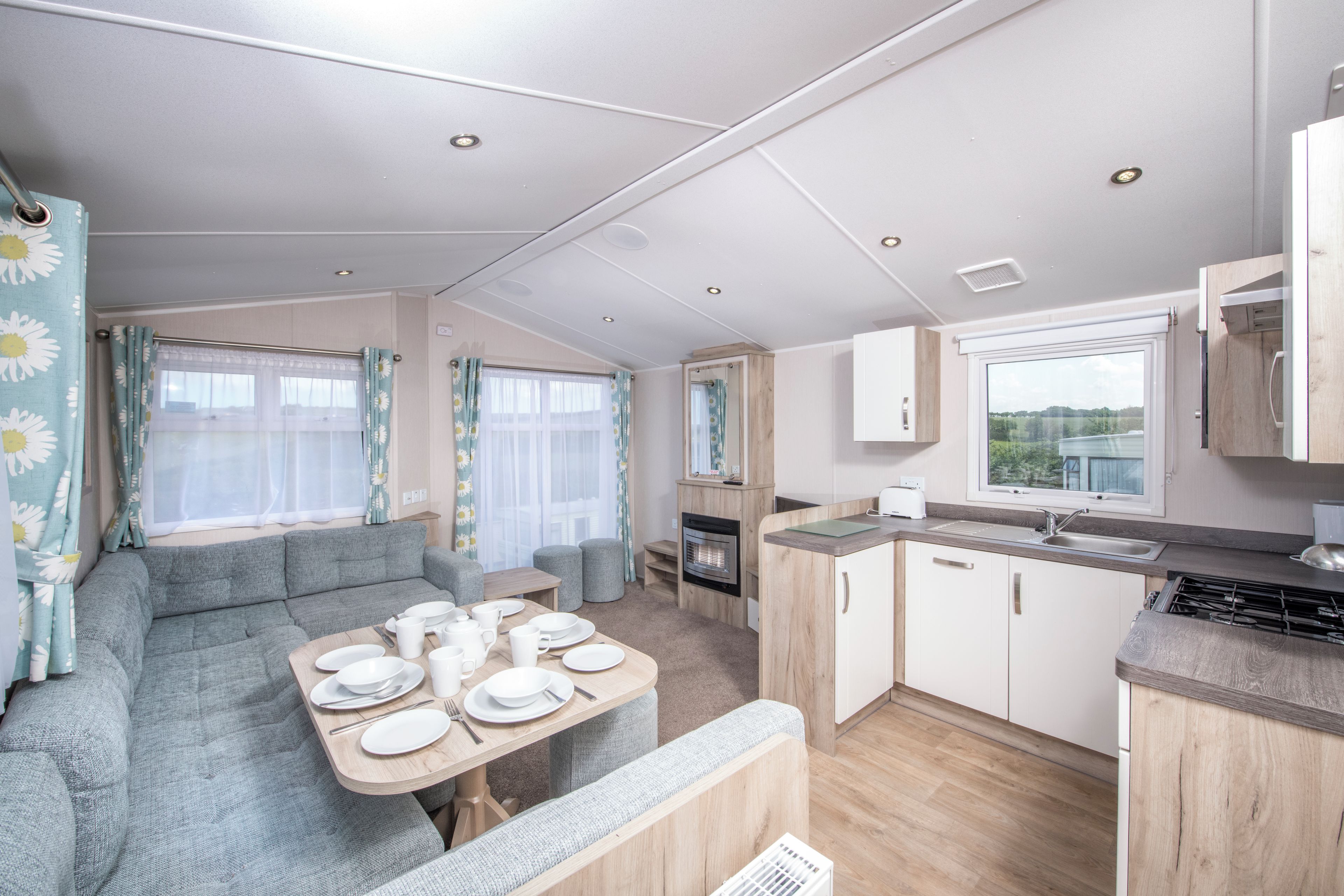 A caravan interior with a dining area, kitchenette, and seating space.
