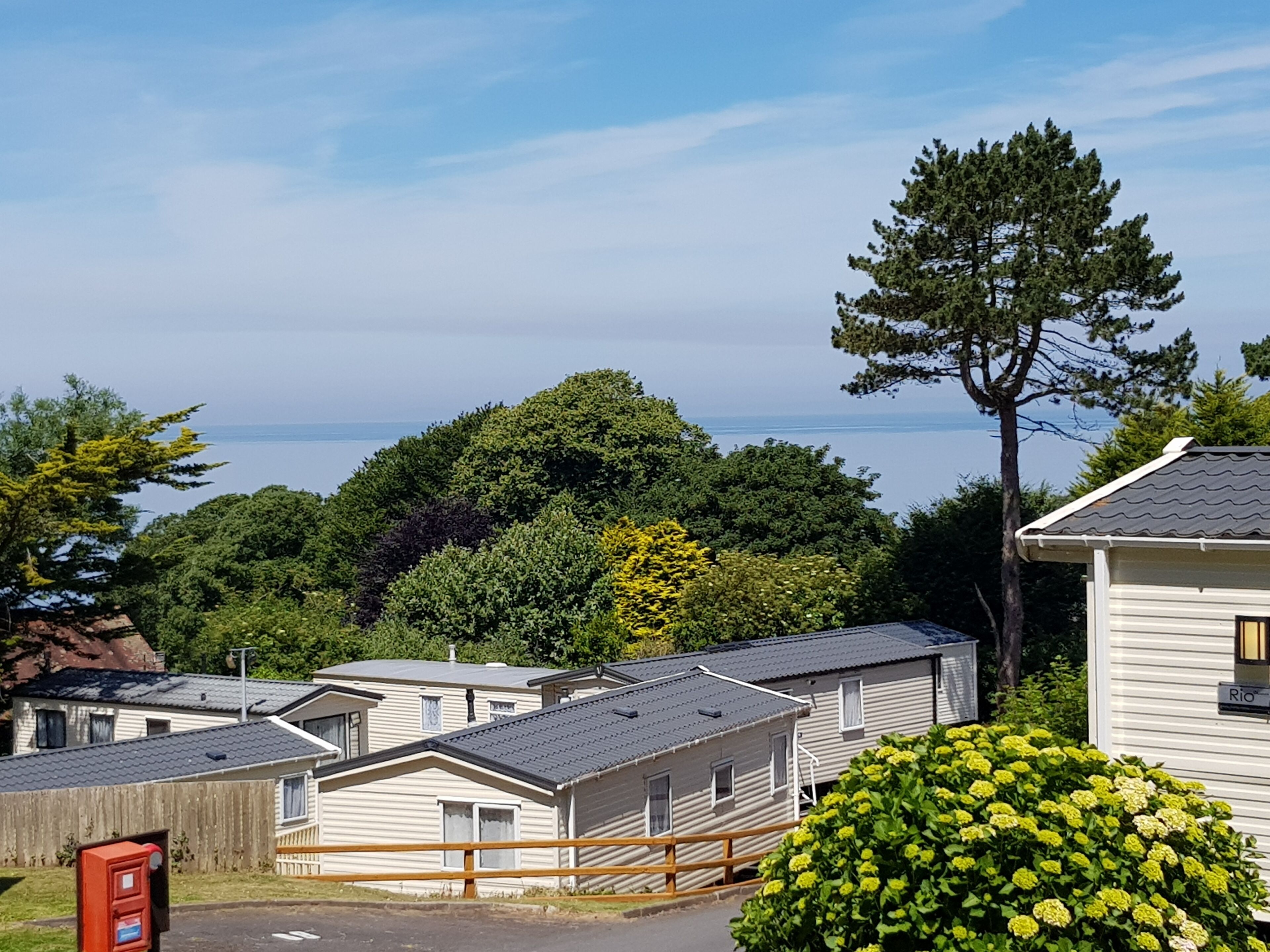 Une rangée de maisons mobiles avec vue sur la mer et une colline boisée en arrière-plan.