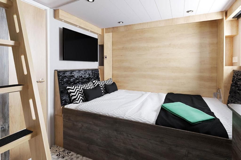 Une chambre moderne avec un cadre de lit en bois, un téléviseur fixé au mur et une armoire intégrée.