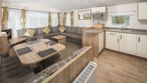 A compact RV interior with a dining area, kitchenette, and seating space. - Sandaway Beach Holiday Park (Ilfracombe)