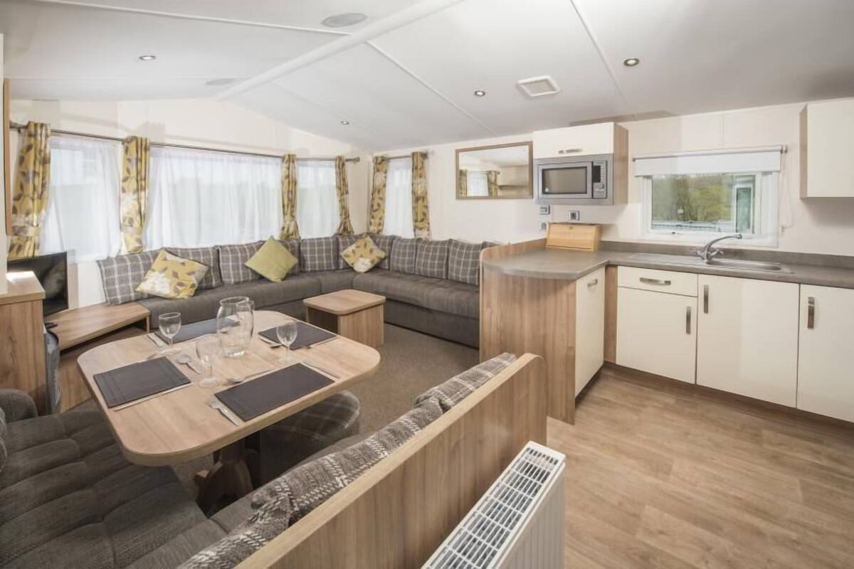 A compact RV interior with a dining area, kitchenette, and seating space.