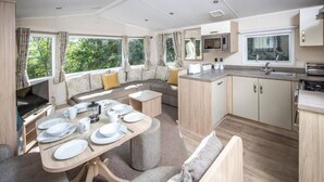 A compact, modern RV kitchen with a dining area, a microwave, and a sink. - Sandaway Beach Holiday Park (Ilfracombe)