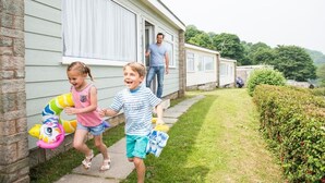A residential setting with a house and a mobile home in the background. - Sandaway Beach Holiday Park (Ilfracombe)