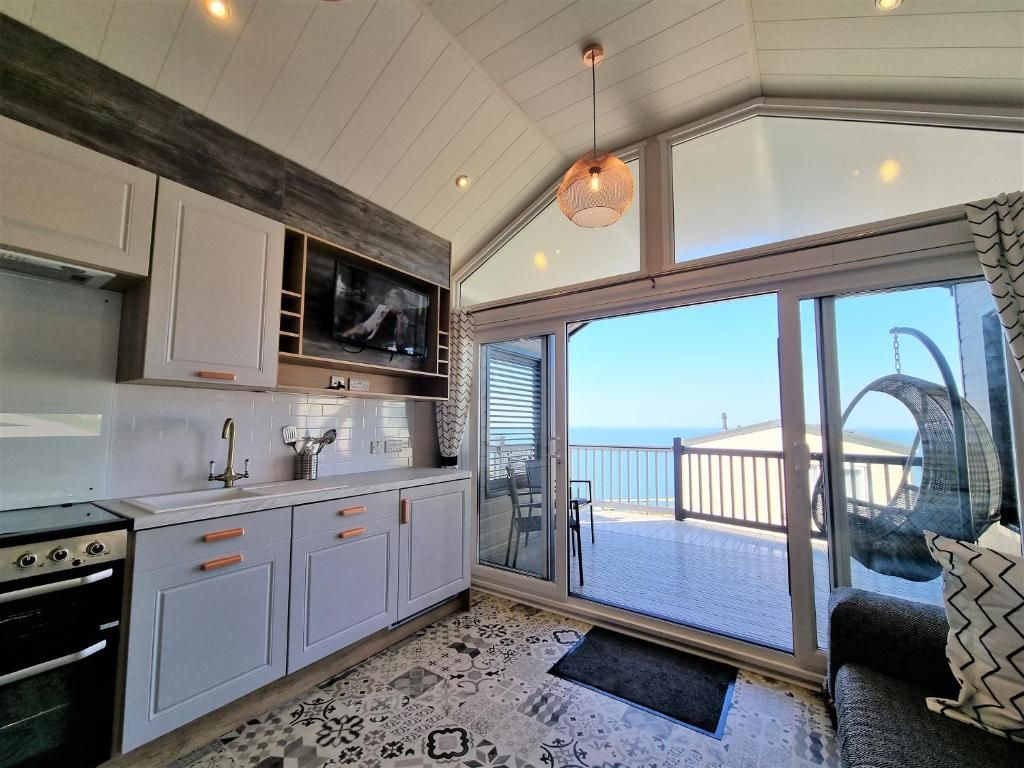 A modern kitchen with a large window, a dining area with a view, and a balcony with a view.