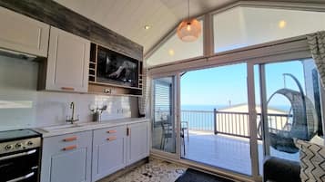 A modern kitchen with a large window, a dining area with a view, and a balcony with a view.