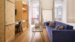 Una sala moderna con un sofá azul, piso de madera y un mueble de madera.