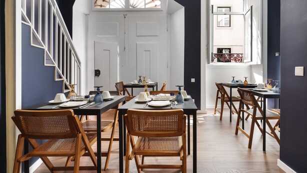 Un comedor con sillas y mesas de madera, puertas blancas y una escalera.