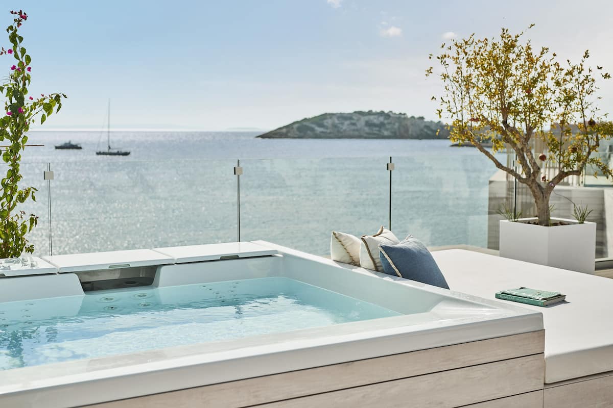 En modern utomhusbubbelpool med utsikt över havet och båtar.