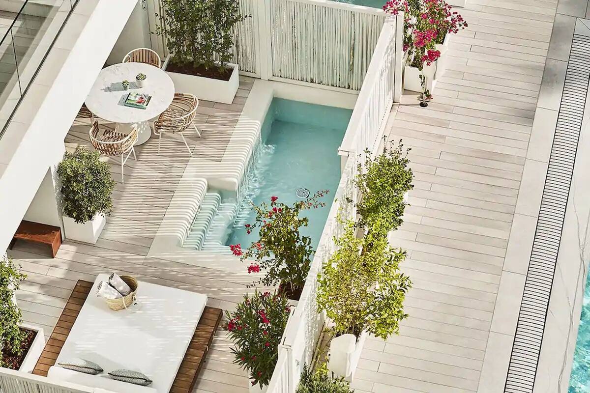 En takterrass med en pool, utomhusmöbler och planterade blommor i krukor.