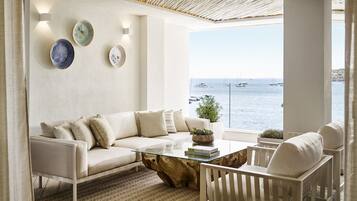 Una sala de estar moderna con un sofá blanco, una mesa de centro de vidrio y vista al mar.