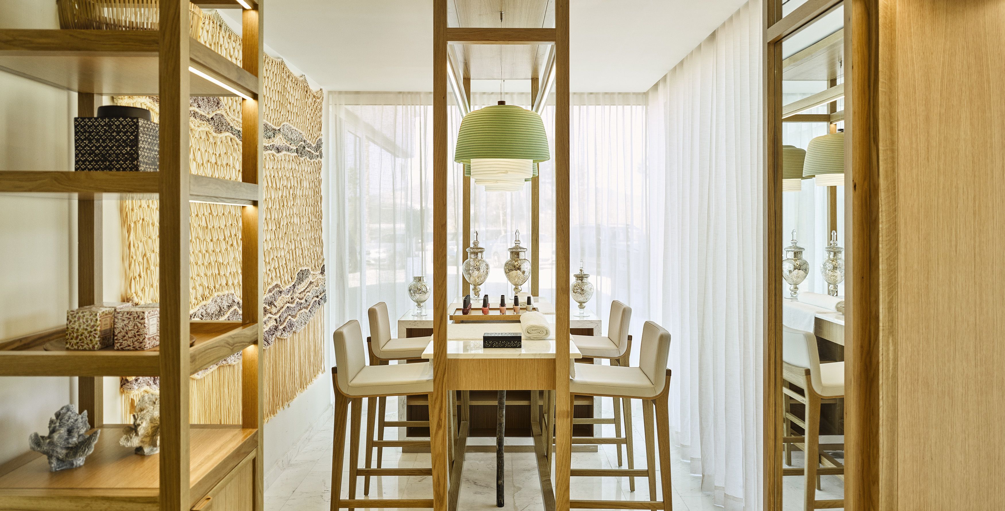 A dining area with a wooden table, six chairs, and hanging green lamps.