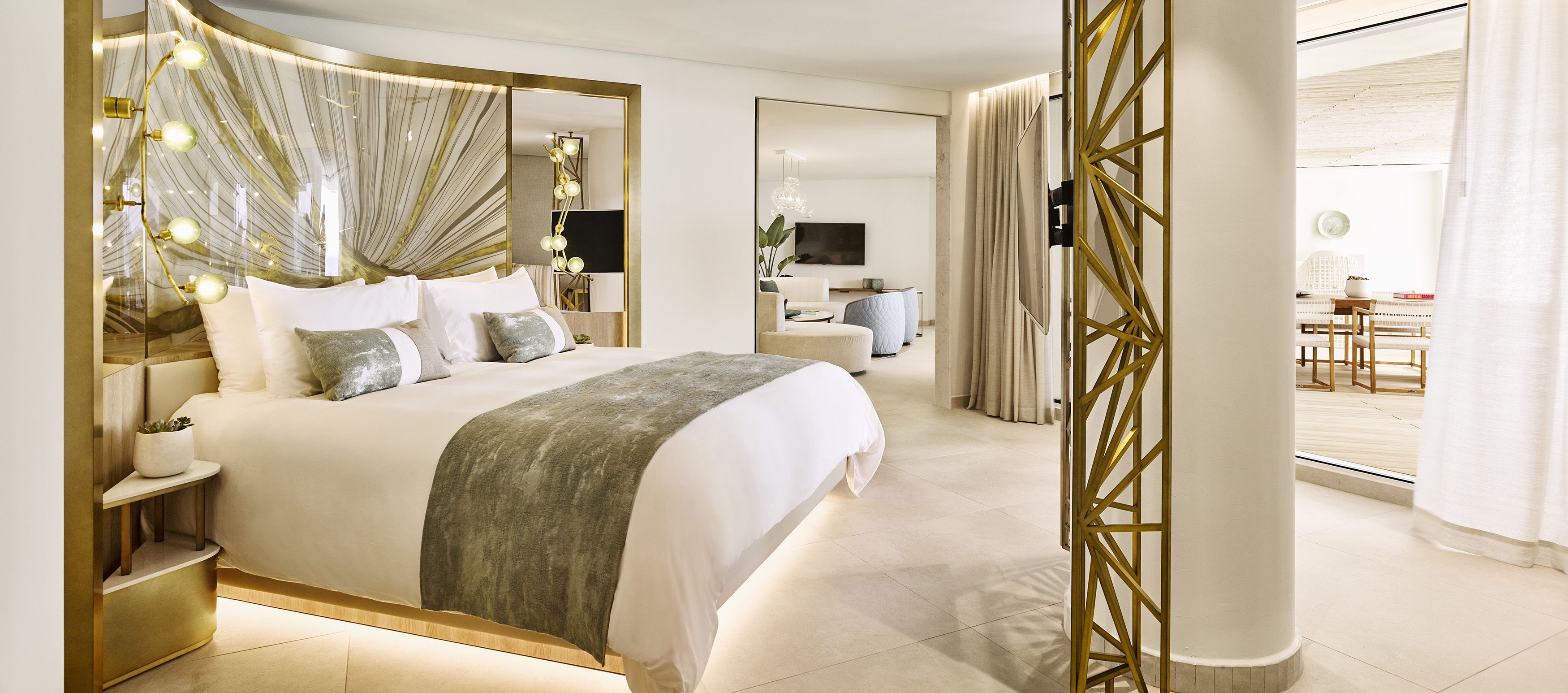 Een moderne hotelkamer met een groot bed, nachtkastjes, een spiegel en uitzicht op de ontbijtruimte.