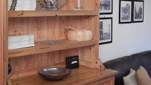 A wooden shelf unit with various items including books, a bowl, and a decorative jar. - LETS Quiet Cul-de-Sac Apartment (Cambridge)