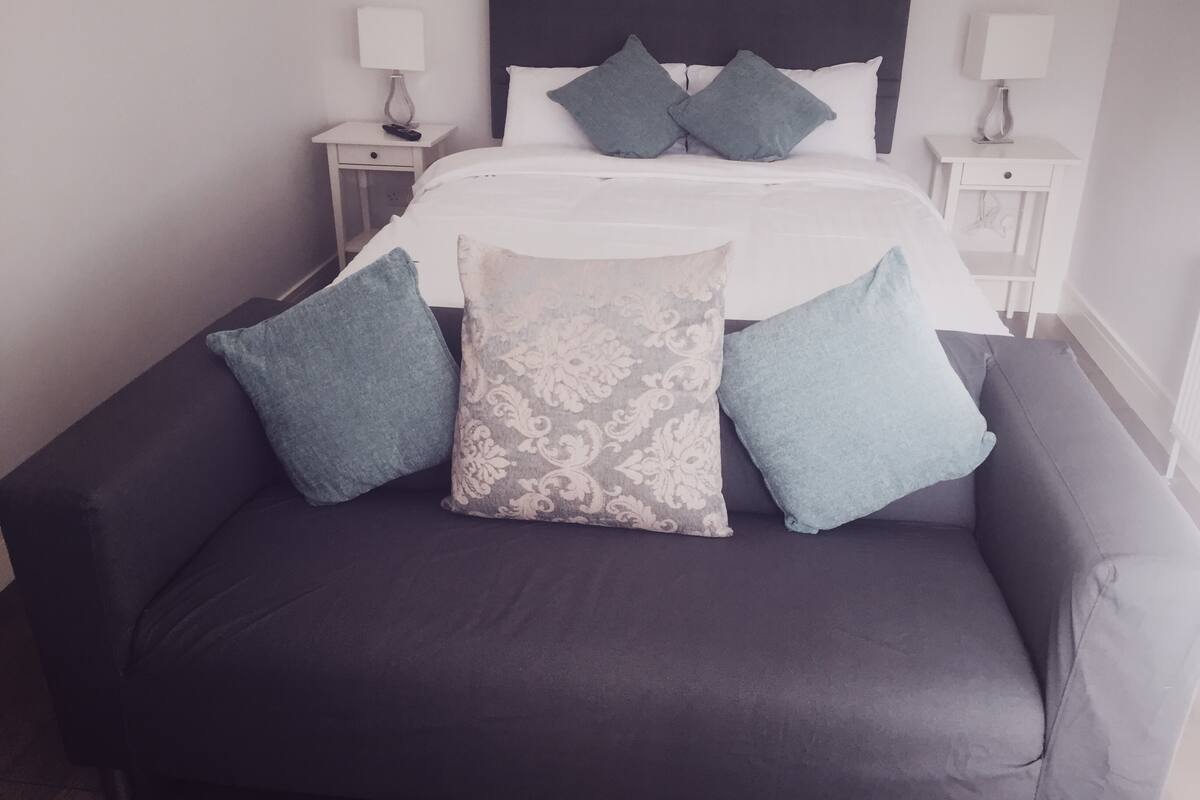 A neatly made bed with a dark headboard, flanked by two bedside tables with lamps.