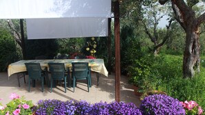 An outdoor patio with a table and chairs, surrounded by potted plants and trees. - B&B La Terrazza Di Frascati (Monte Porzio Catone)