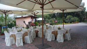 An outdoor patio with round tables set for dining, surrounded by umbrellas and chairs. - B&B La Terrazza Di Frascati (Monte Porzio Catone)