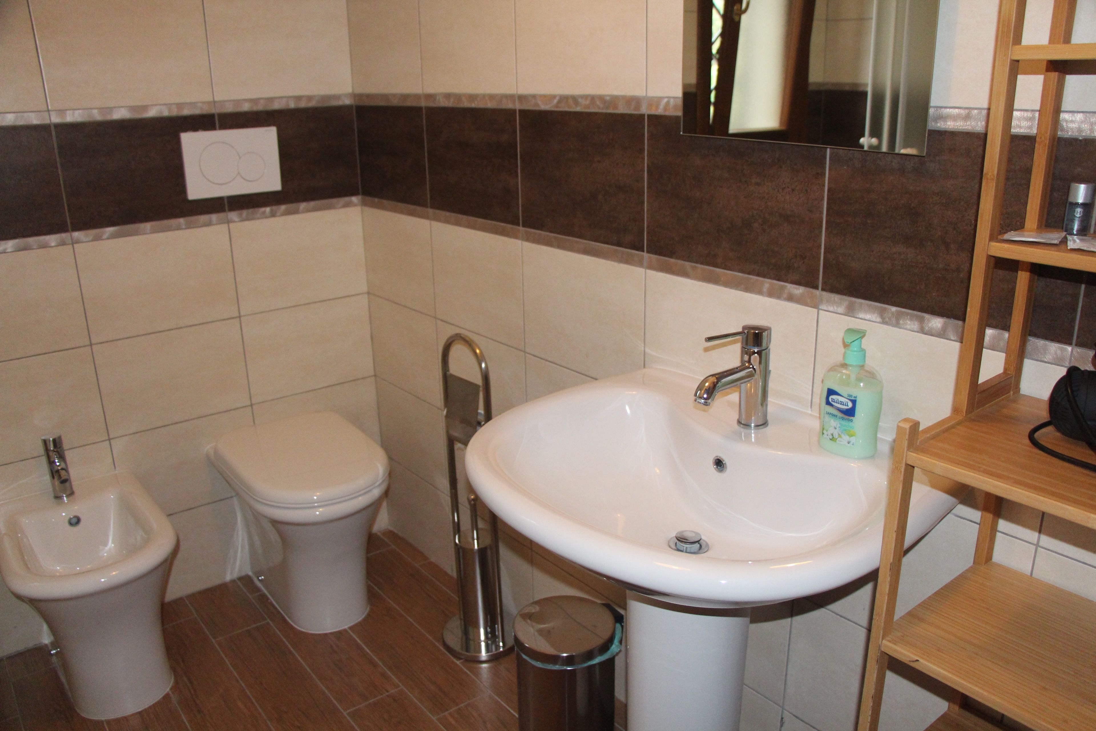 A bathroom with a bidet, toilet, sink, and mirror.