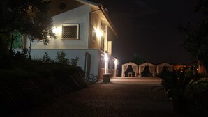 A two-story building with a paved driveway leading to a covered outdoor area. - B&B La Terrazza Di Frascati (Monte Porzio Catone)