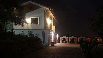 Een gebouw met twee verdiepingen en een geplaveid pad dat leidt naar een overdekt terras.