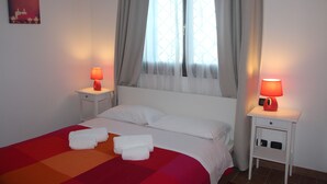 A hotel room with a bed, two bedside tables with lamps, a window with curtains, and a wall-mounted picture. - B&B La Terrazza Di Frascati (Monte Porzio Catone)