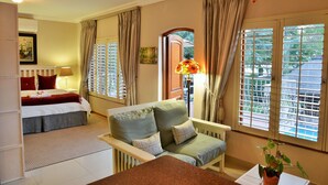 Een hotelkamer met een bed, een bank, een eettafel en een raam met luxaflex.