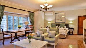 Een hotelkamer met een eettafel, een bank, een bed en een kroonluchter.