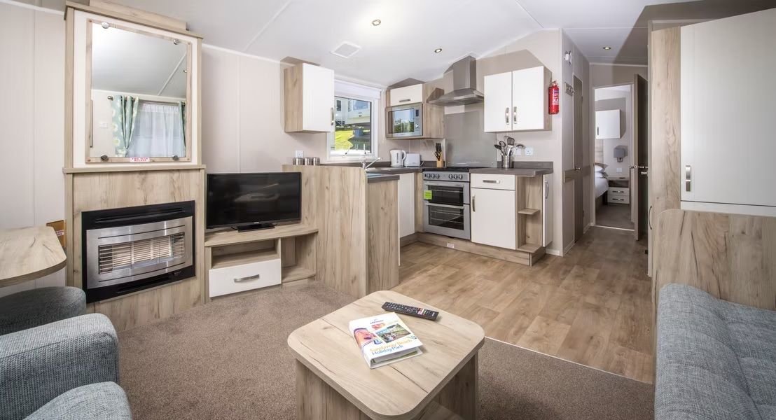 Un espacio habitable compacto con kitchenette, televisor y zona de estar.