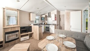 A modern RV kitchen with a dining area, including a TV, microwave, and stove. - South Bay Holiday Park (Brixham)
