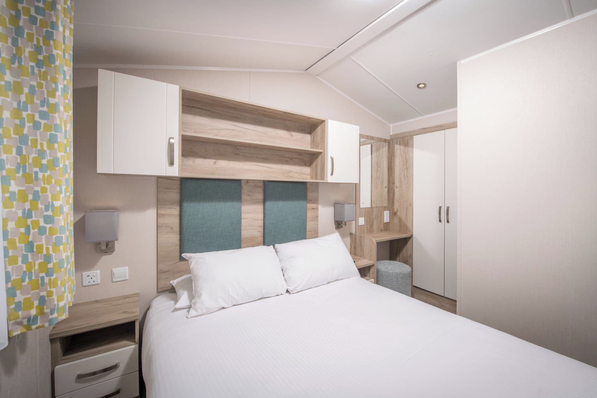 Een hotelkamer met een bed, een kledingkast, een nachtkastje en een bijzettafeltje.