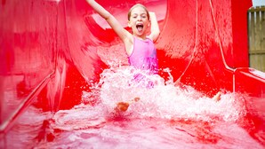 A child sliding down a red water slide. - South Bay Holiday Park (Brixham)