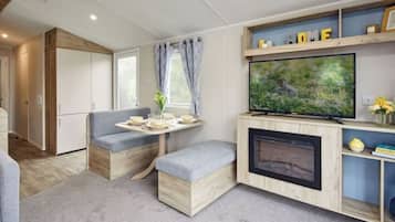 A compact living space with a sofa, a small table with a vase, a television, and a fireplace.