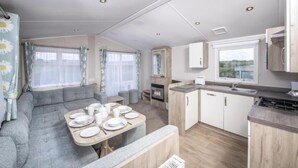 A compact RV interior with a dining area, kitchenette, and seating. - South Bay Holiday Park (Brixham)