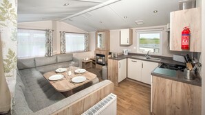 A compact RV kitchen with a dining area, a built-in oven, and a sink. - South Bay Holiday Park (Brixham)