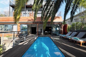 A modern outdoor pool area with lounge chairs and a wooden deck.