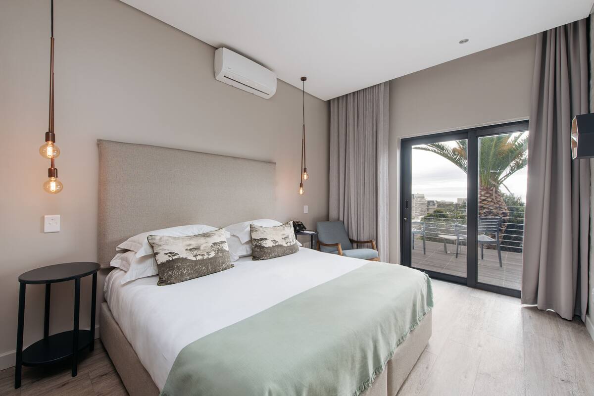 Een moderne slaapkamer met een groot bed, een klein nachtkastje, een stoel en een balkon met uitzicht.