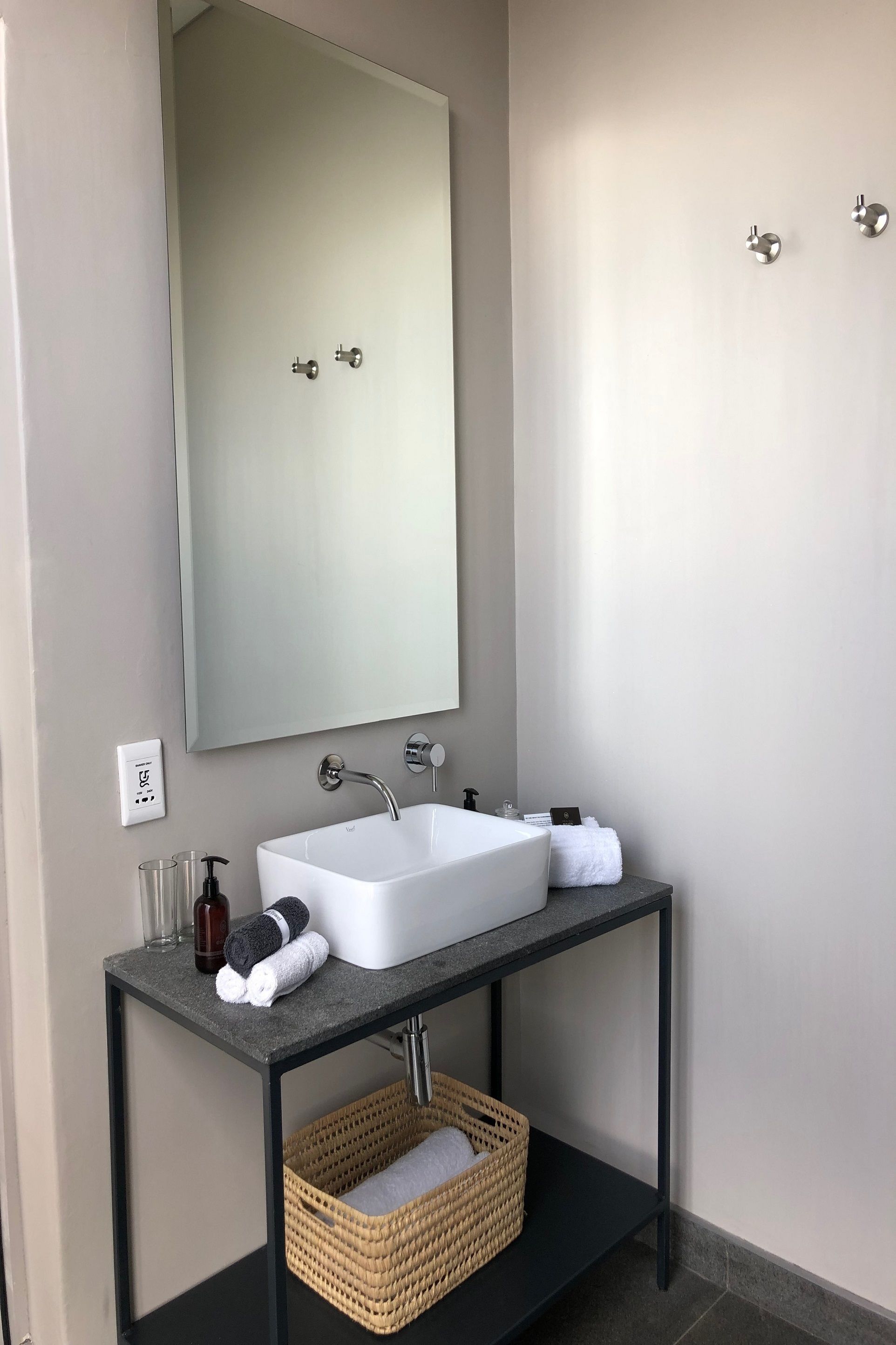 Un baño moderno con un lavamanos blanco, un espejo grande y un mueble de tocador negro.