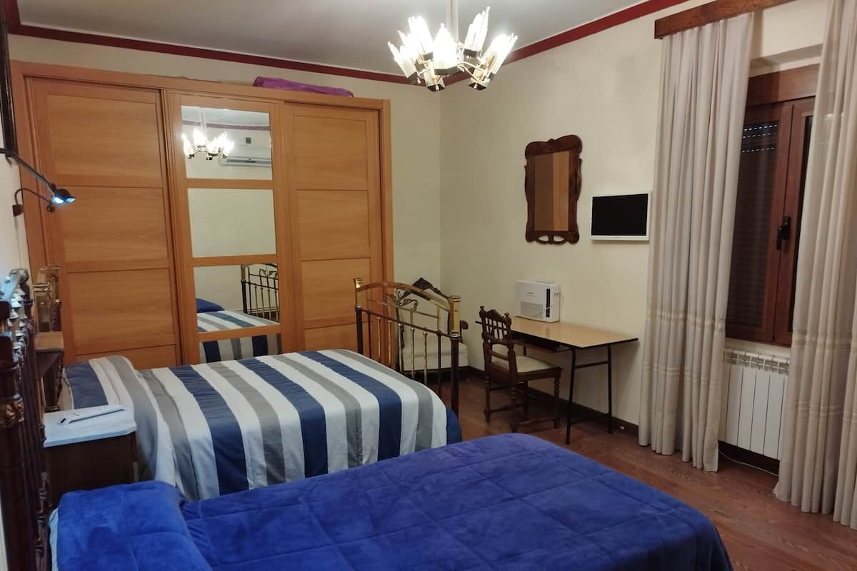Une chambre avec deux lits, un bureau, une chaise, un miroir et un radiateur.