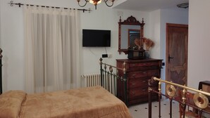 A bedroom with a bed, a dresser, a mirror, a television, and a chandelier. - Casa Rural el Rincon del Infante (Villa de Don Fadrique)