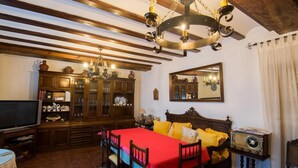 A traditional room with a wooden ceiling, a bed with yellow bedding, a wooden cabinet with glass doors, a television, and a vintage radio. - Casa Rural el Rincon del Infante (Villa de Don Fadrique)