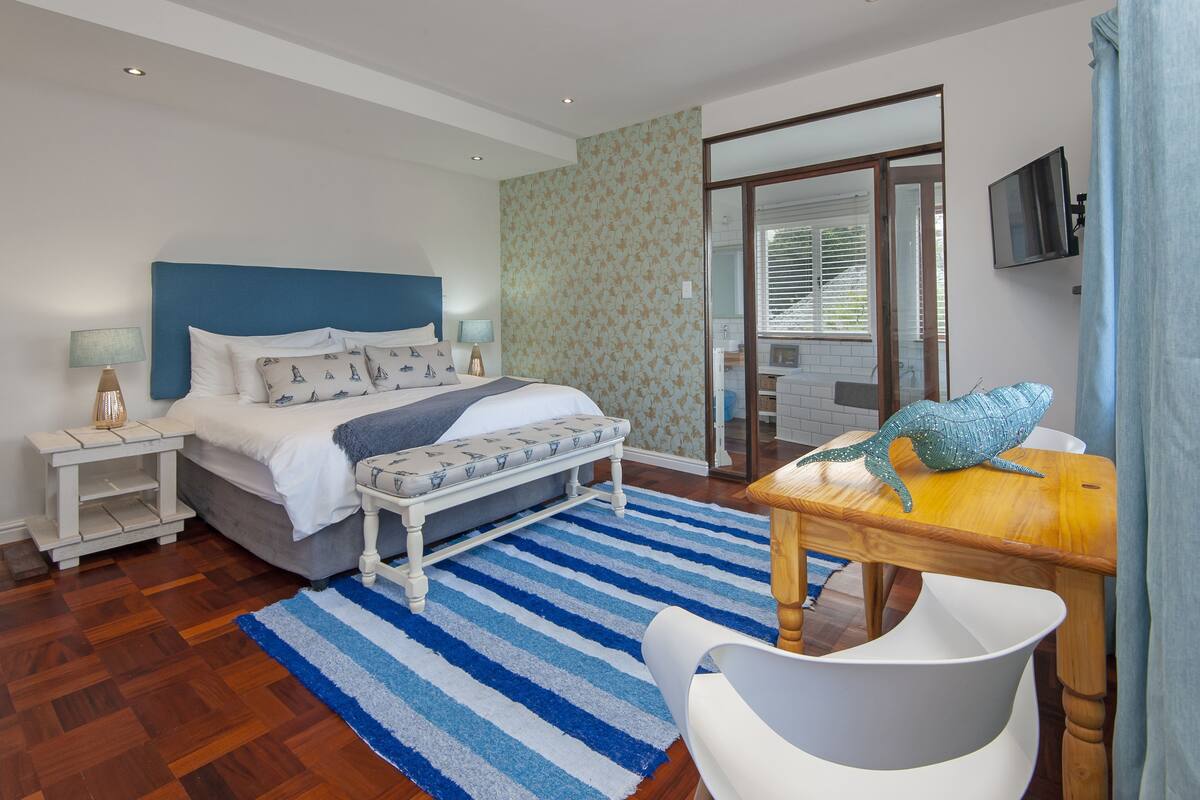 A bedroom with a bed, bedside tables, a desk, and a chair.