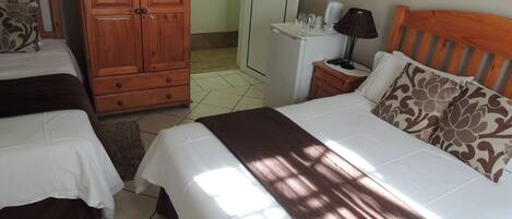 Una habitación de hotel con dos camas, un armario de madera, una mesita de noche con lámpara y un adorno en la pared.