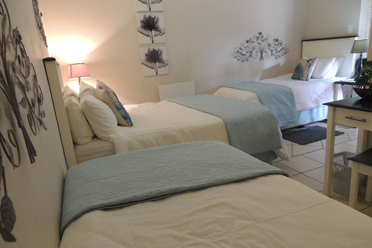 Ein Hotelzimmer mit zwei Betten, einem Schreibtisch und einem Stuhl. An den Wänden befinden sich Dekorationen und eine Lampe.