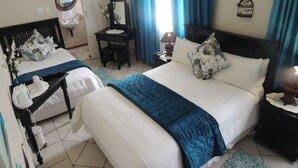 A hotel room with two beds, a desk, a chair, a lamp, and a window with curtains. - Rita Guest House (Abaqulusi)