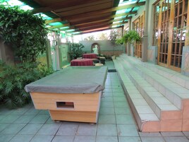 Mesa de bilhar em área externa coberta, com degraus que levam a um edifício.